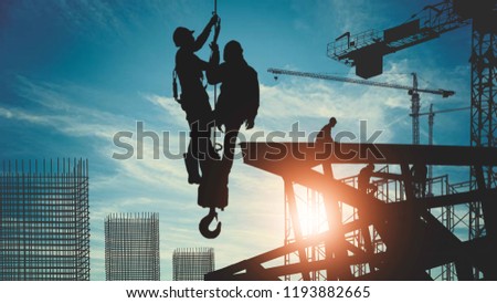 silhouette of construction workers working in high places with crane hoist wire sling welding truss of constructure Royalty-Free Stock Photo #1193882665
