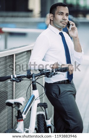 Dreamy businessman planning his day while arranging meeting talking on phone. Pensive purposeful young Hispanic lawyer using mobile phone outdoors. Communication concept