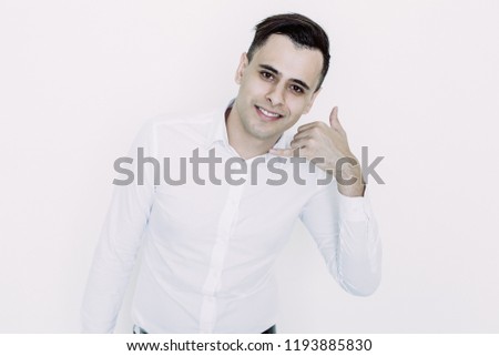 Closeup portrait of smiling young handsome man looking at camera and making call me gesture. Communication concept. Isolated front view on white background.