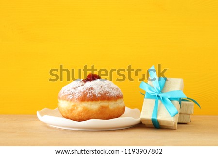 Image of jewish holiday Hanukkah with present box and donut on the table
