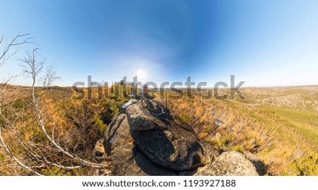 Couple of tourists with backpacks man and woman standing on a rock in autumn forest panorama