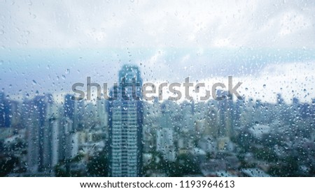 Rainy season, Rain drops on window's glass is viewing the downtown city skyline on a dark weather day. Abstract rain drop/raining scenery background - can be used for display or montage your products.