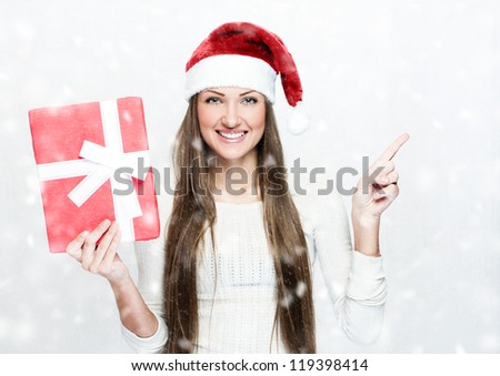 young smiling woman in santa hat , holds christmas gift , snow