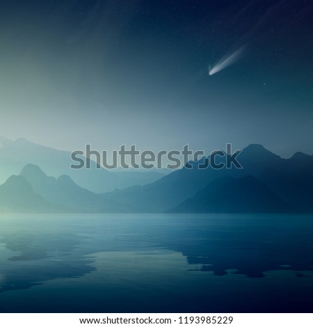Beautiful mysterious nature background. Bright comet and stars in dark blue sky, silhouettes of mountains reflected in a calm sea