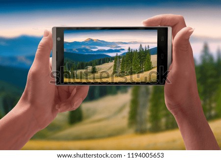Panorama of Carpathian mountain valley on a screen of smartphone taking by girl hands. Travel and adventure concept.