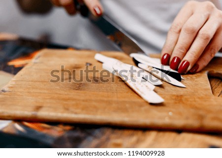 Eggplant cutting on wooden desk by unrecognizable woman.
