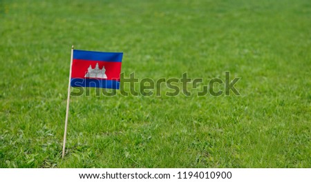Cambodia Flag. Photo of Cambodian flag on a green grass lawn background. National flag waving outdoors.