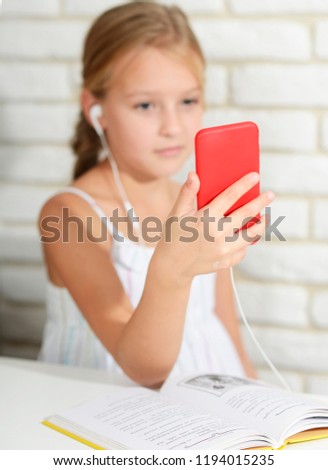 phone instead of a book a schoolgirl sits in a smartphone with headphones, listens to music and does not do lessons social dependence problem of children new generation social networks children