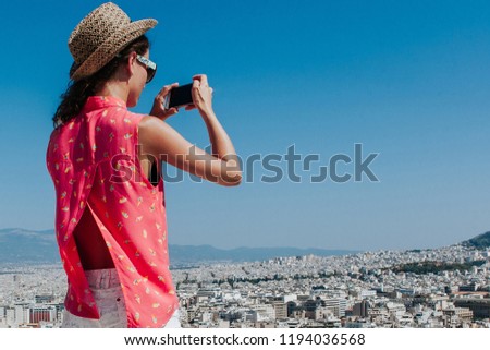 Tourist taking picture from view point. Girl with backpack, camers and hat. Travel concept.