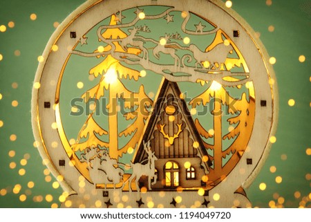 Image of magical christmas scene of wooden pine forest, hut and santa claus over sleigh with deers