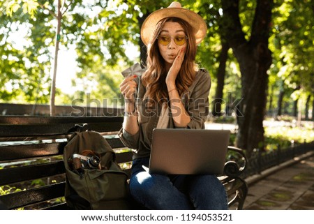 Photo of young beautiful excited happy woman outdoors sitting using laptop computer holding credit card.