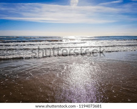 A photo of the blue waters and waves of the Mediterranean Sea. The photo was taken on San Antonio beach. This bathing beach is located in the touristic town of Cullera, in Valencia, Spain, Europe.