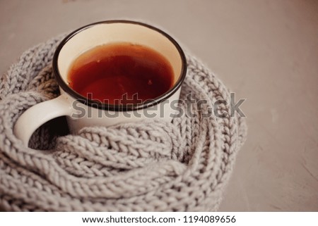 Toned picture with orange and yellow autumn leaves, warm scarf, cup of tea on gray background, top view, with copy space