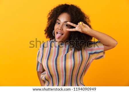 Image of happy young african cute girl posing isolated over yellow background make peace gesture.