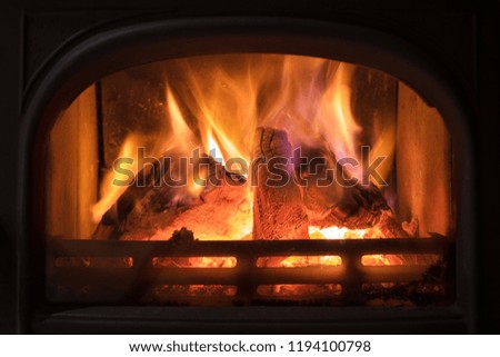 Burning fireplace with wooden logs burning inside. Warm light, romantic, christmas like atmosphere 