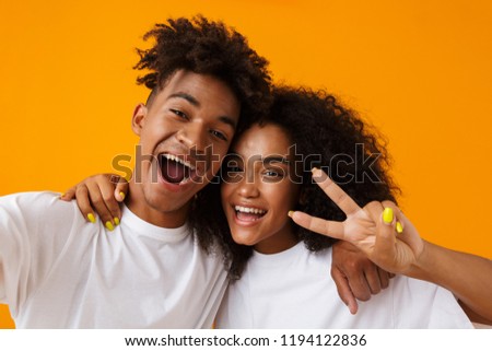 Image of happy young cute african couple posing isolated over beige background showing peace gesture take a selfie by camera.
