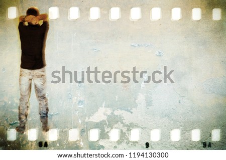 Scratched wall in film strip frame with unrecognizable  figure of young man and blue jeans.