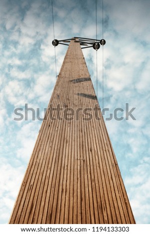 Wooden power transmission line tower in a german countryside. look up view with beautiful blue sky and clouds. Brunswick,  Lower Saxony in Germany