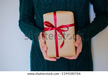 Woman in  sweater hold christmas or new year decorated gift box. Toned picture. Place for text