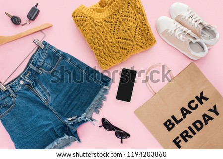top view of stylish clothes, smartphone, car key and shopping bag with black friday sign