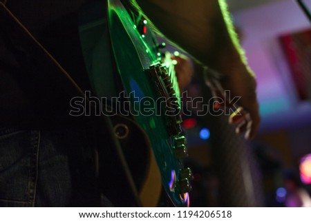 Musician plays bass guitar on stage in neon light