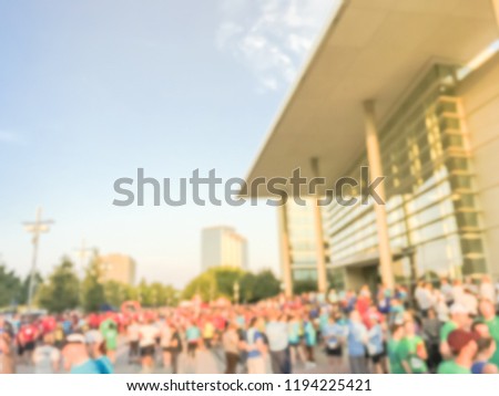 Motion blurred diverse group of runners at sport event with high-rise building in background. Abstract participants of  all abilities at 5K Corporate Challenge race in Richardson, Texas, USA