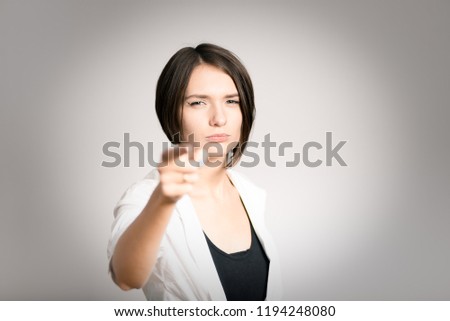 serious girl points at you with a finger, short haircut, isolated above the background