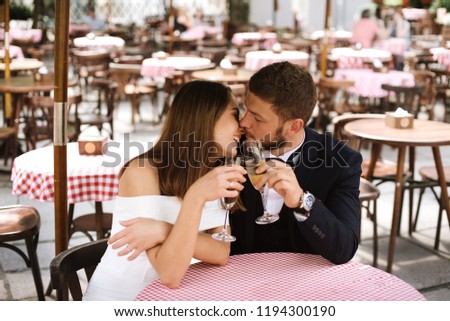 Beautiful couple in cafe having a good time with white wine or champagne outdoor. Love, wedding and togetherness concept.