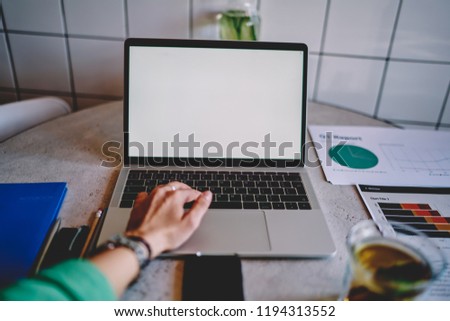 First person view of hand typing text on keyboard of modern laptop device with blank screen area for your internet content or website. Desktop with mock up computer display for advertising information