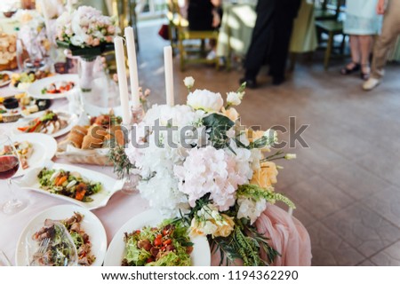 Bouquets of pink and white flowers near the candles on the table.