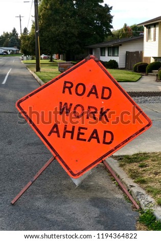 Road work ahead sign posted on the side of the road