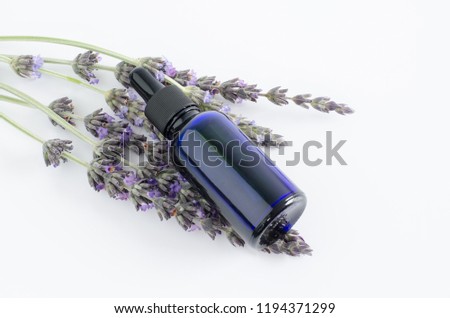 Pot with lavender essential oil on white background with flowers.