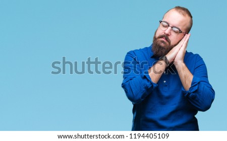 Young caucasian hipster man wearing glasses over isolated background sleeping tired dreaming and posing with hands together while smiling with closed eyes.