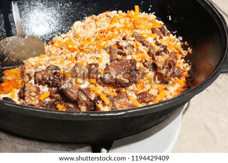 Traditional Uzbek pilaf with lamb meat cooked in a large cauldron