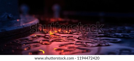   Raindrops on a glossy surface suspended by neon light. The lights of the city at night in puddles on the pavement. Dark abstract background, blur bokeh.
