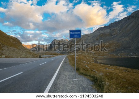 Mountain pass road named Fluela. Street sign in the Swiss alps. Beautiful autumn sunset in Switzerland, Europe. Perfect weather for a road trip in the country side.