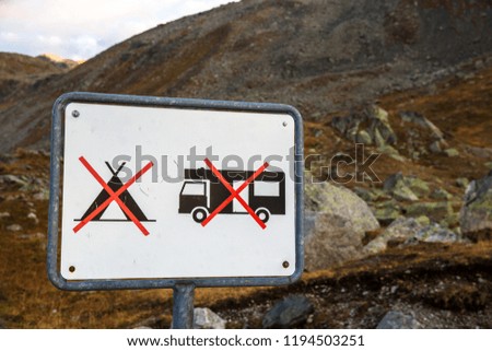 Prohibited sign for camping cars, caravans and tents. Camping sign in the mountains. Wild camping is prohibited in the mountain area in Switzerland. Street sign in the landscape. No tenting.