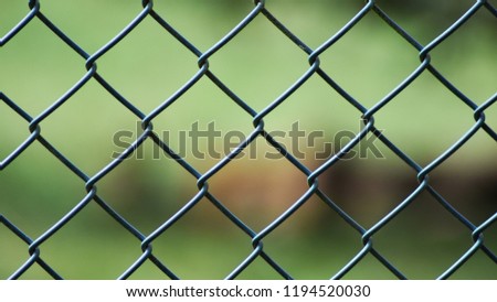 Close up of a green grey metal covered in plastic coating chain link fence gate outside with a green background. Royalty-Free Stock Photo #1194520030