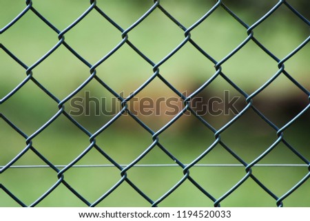 Close up of a green grey metal covered in plastic coating chain link fence gate outside with a green background.