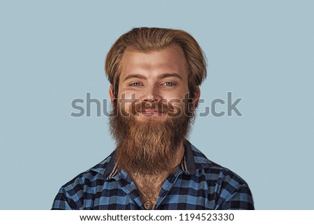 Closeup portrait happy young man. Hipster male with beard in blue plaid checkered shirt  Isolated on blue studio Background. Negative face expression, human emotion, body language, reaction, attitude.