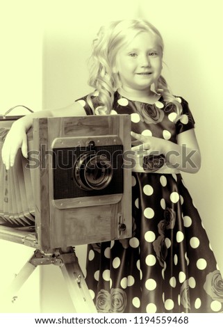 A nice little girl near a large studio camera. Retro style.