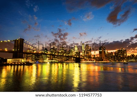 New York, USA. View of Manhattan bridge and Manhattan in New York, USA at sunset. Colorful cloudy sky with illuminated skyscrapers. Sun setting behind the skyscrapers