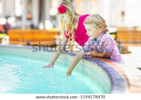 Cute Young Caucasian Brother and Sister Enjoying The Fountain At The Park.