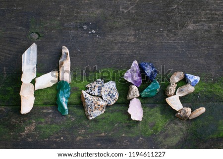 Gems and rocks spelling out words on a mossy wooden background