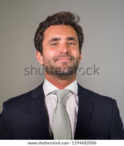 young elegant and handsome happy man in suit posing for company corporate business portrait relaxed and confident smiling happy isolated on grey as successful ceo executive businessman 