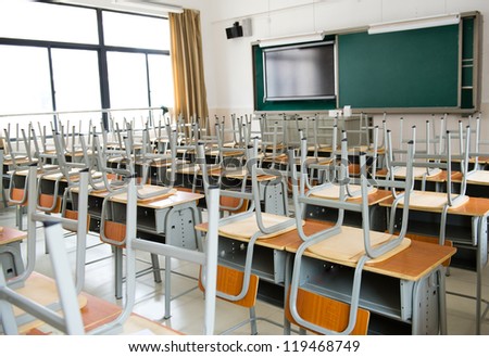 Empty classroom with chairs, desks and chalkboard.