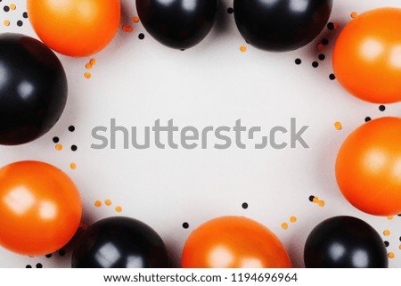Black and orange balloons and confetti frame for Halloween card or invitation. Flat lay.