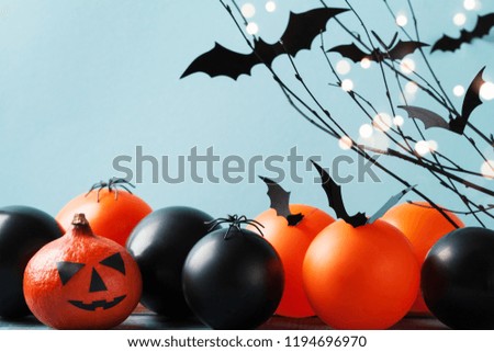 Halloween card with funny pumpkin head, flying bat, black and orange balloons on turquoise background.