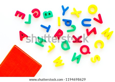 Children learn read concept. Plastic letters of toy alphabet near book on white background top view