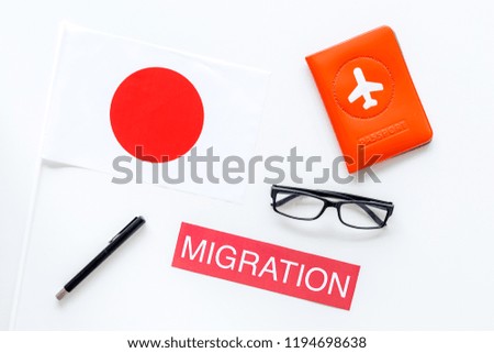 Immigration to Japan concept. Text immigration near passport cover and japanese flag on white background top view